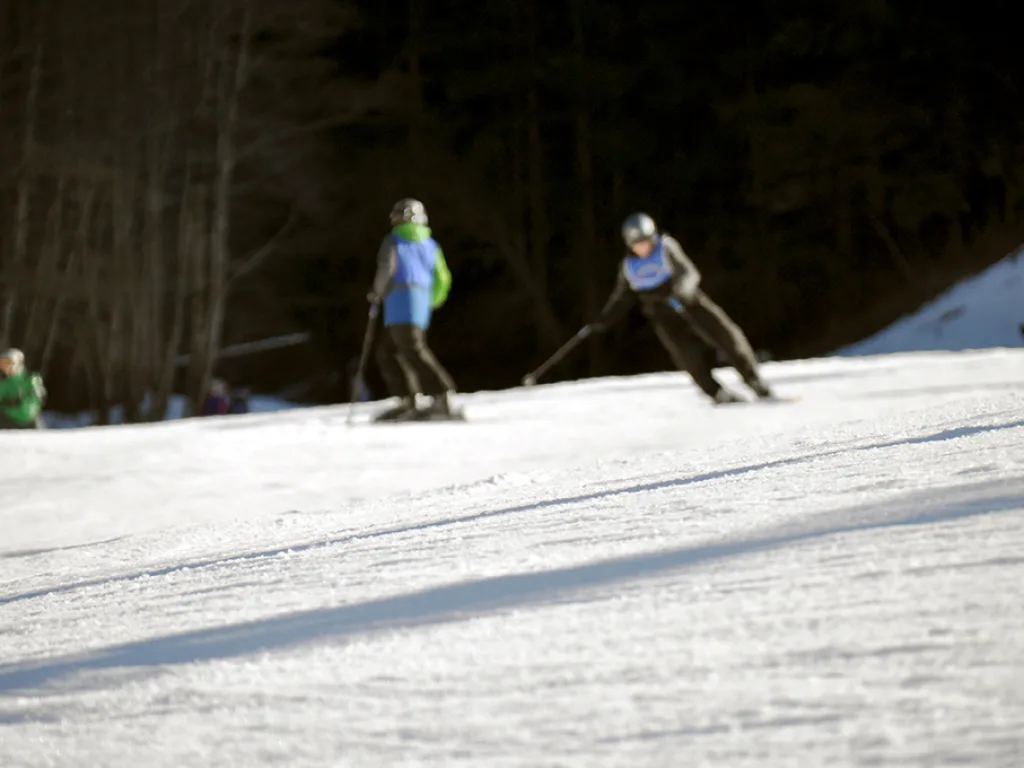 Zwei Skifahrende auf der Piste im Abendlicht.